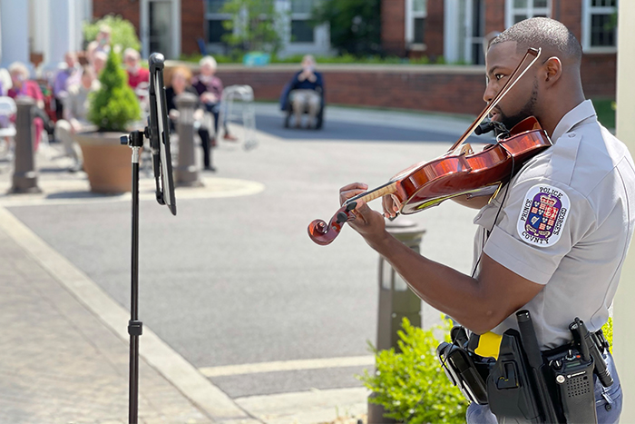 Alex Strachen playing violin in uniform at community event