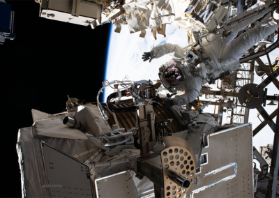 Astronaut waving in space, beside UTTPS EVA Data and Power Cables